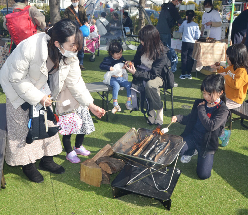 焚き火でマシュマロを味わう家族