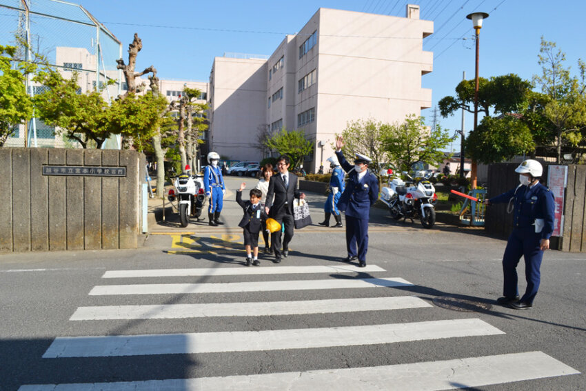 入学式を終えて、元気に横断歩道を渡る新入学児童と保護者