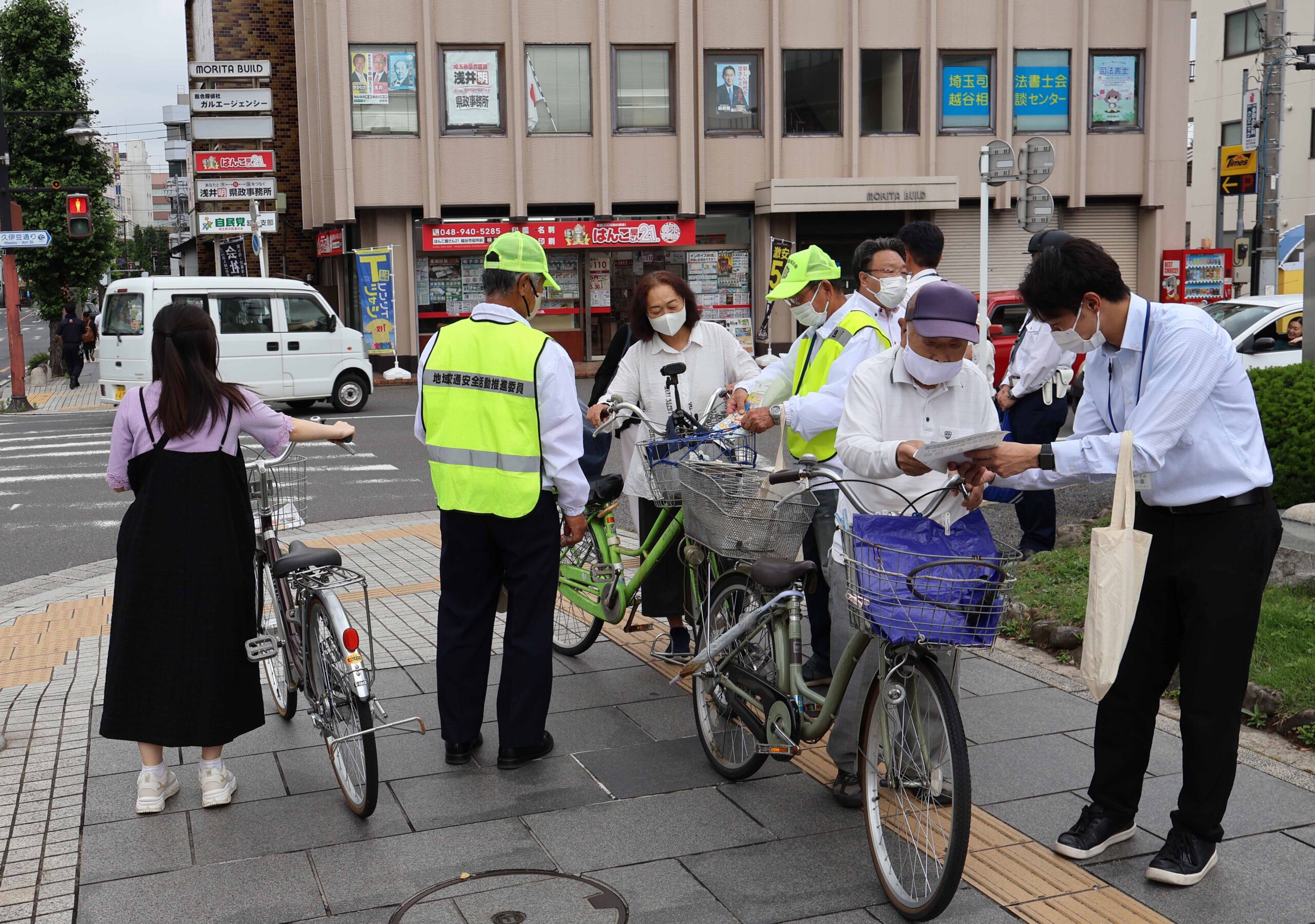 自転車の利用者にヘルメット着用などを呼びかける越谷署員ら