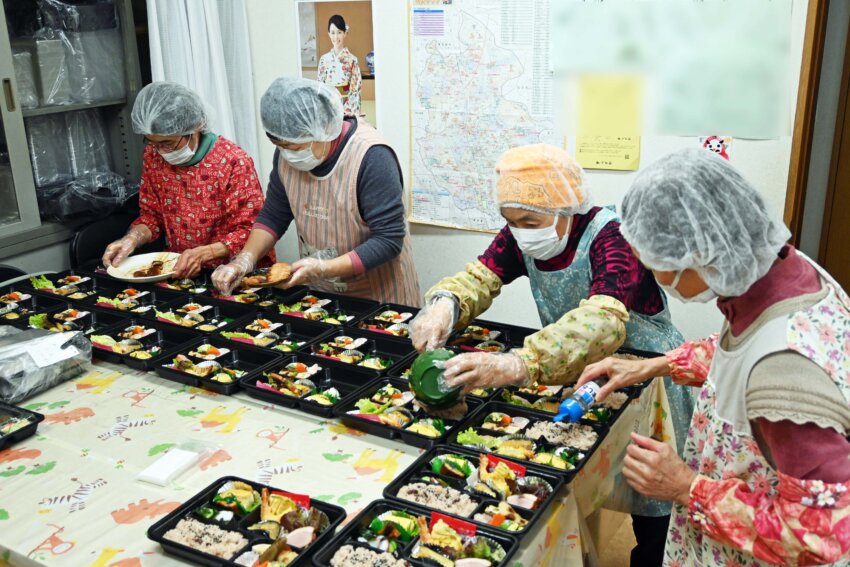 大量の弁当を手際よく作るキッチンとまとのスタッフ