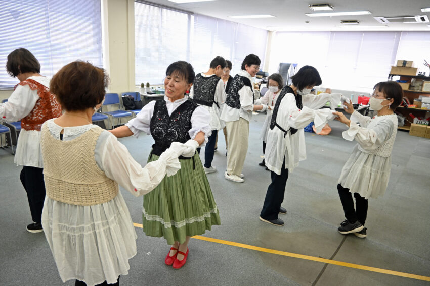 白いブラウスに耳飾りをつけて踊る会員ら